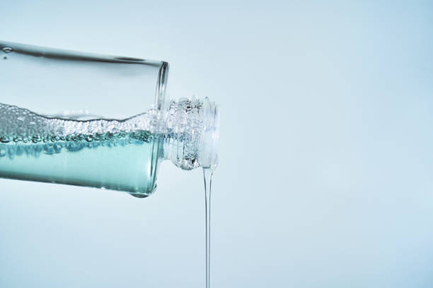 Cosmetic bottle from which serum is pouring on a blue background. High quality photo.